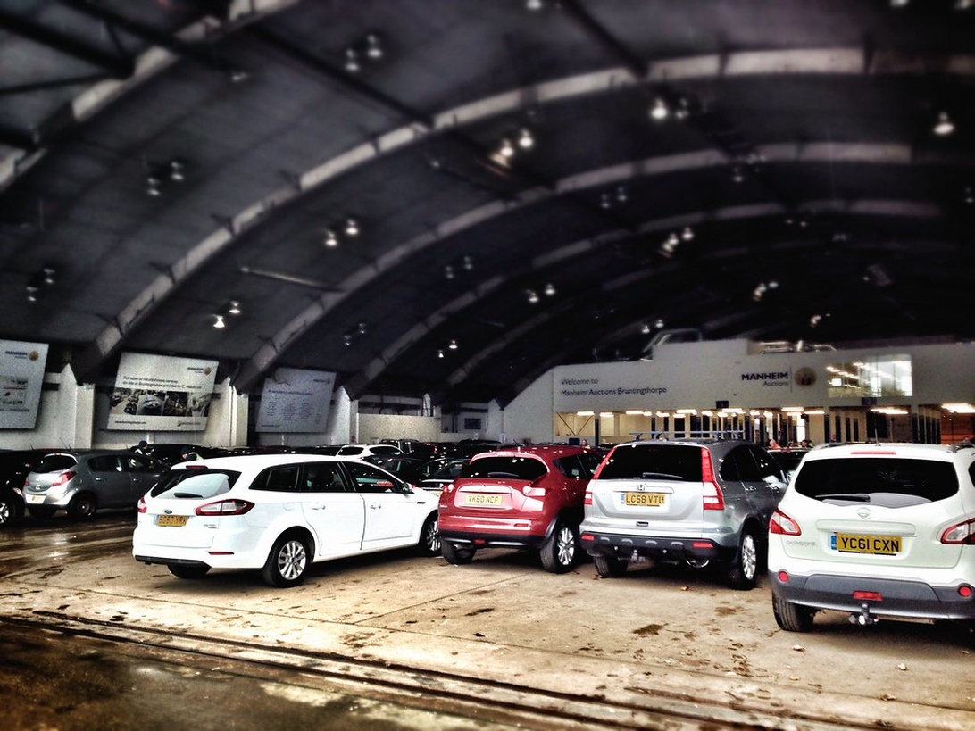 Interiör från Manheim Auctions anläggning med flera bilar parkerade i en stor täckt arena.